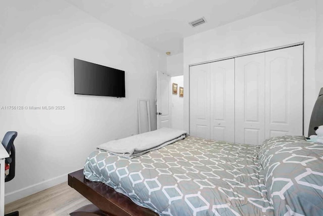 bedroom featuring baseboards, a closet, visible vents, and wood finished floors