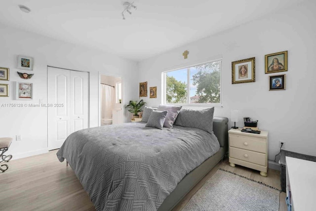 bedroom with ensuite bathroom, a closet, light wood-type flooring, and baseboards