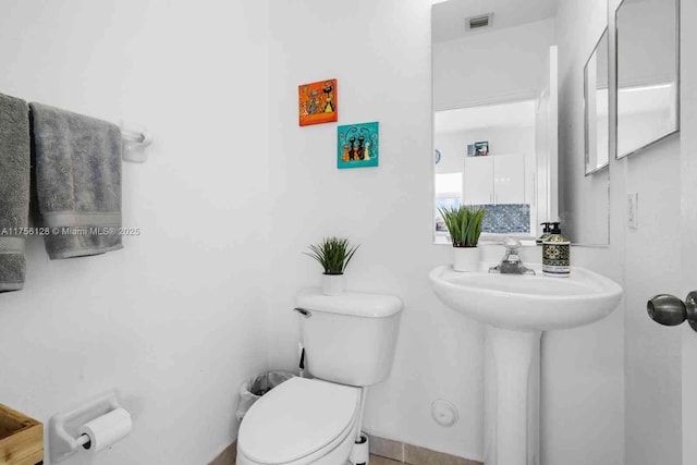 half bath featuring visible vents, a sink, and toilet