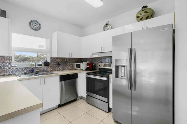 kitchen featuring under cabinet range hood, stainless steel appliances, a sink, white cabinets, and decorative backsplash