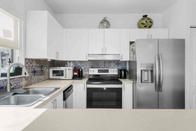 kitchen featuring under cabinet range hood, stainless steel appliances, a sink, light countertops, and decorative backsplash