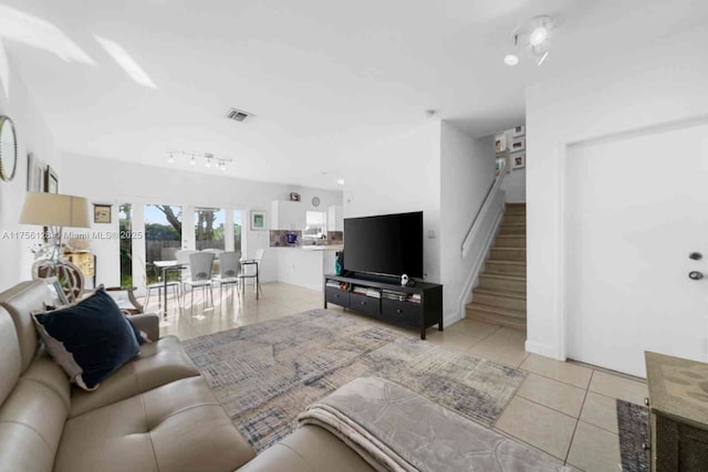 living area with light tile patterned floors, stairway, and visible vents