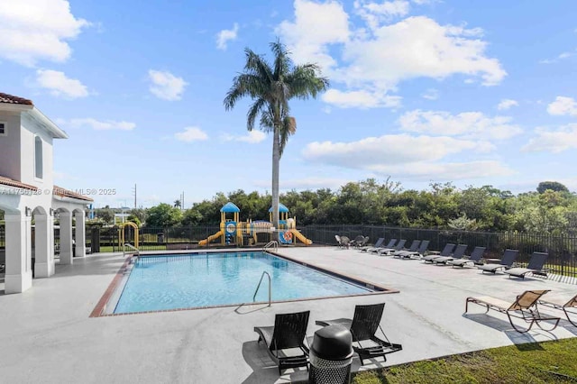 pool featuring playground community, a patio, and fence