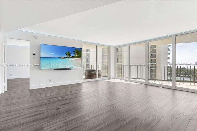 unfurnished living room with baseboards, floor to ceiling windows, and wood finished floors