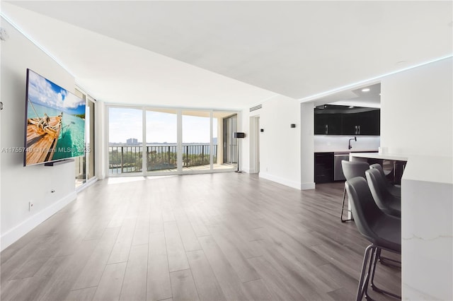 living room featuring expansive windows, baseboards, and wood finished floors