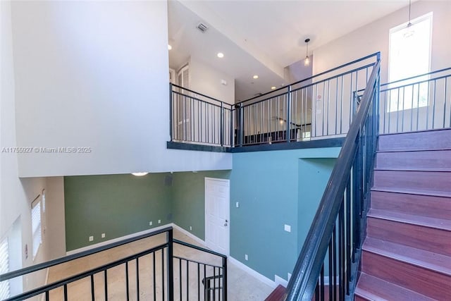 stairs with recessed lighting, a high ceiling, visible vents, and baseboards