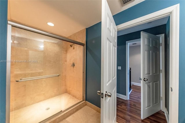 bathroom featuring wood finished floors, a shower stall, visible vents, and baseboards