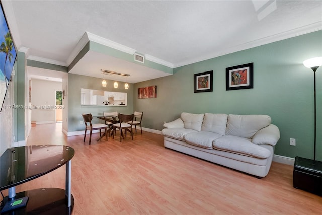 living area with baseboards, visible vents, wood finished floors, and ornamental molding