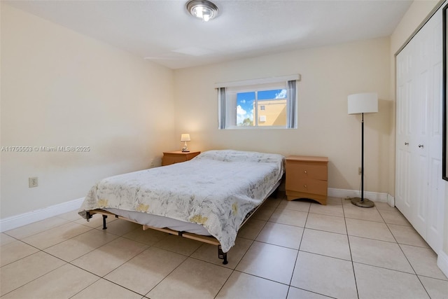 bedroom with light tile patterned floors, a closet, and baseboards