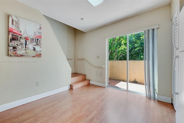 unfurnished room with stairs, wood finished floors, and baseboards