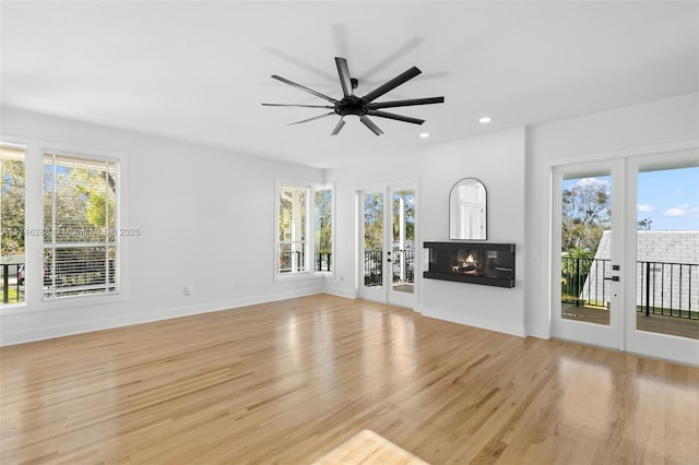 unfurnished living room featuring french doors, a multi sided fireplace, light wood-style flooring, and recessed lighting