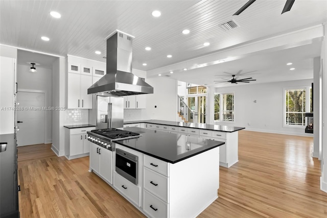 kitchen featuring stainless steel appliances, visible vents, a center island, dark countertops, and island exhaust hood