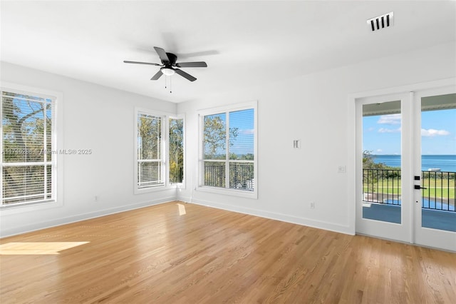 empty room featuring a healthy amount of sunlight, light wood-style floors, baseboards, and visible vents