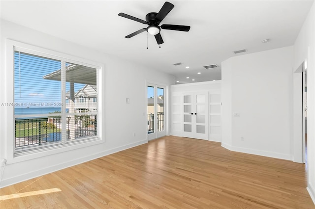 unfurnished room with light wood-type flooring, visible vents, and baseboards