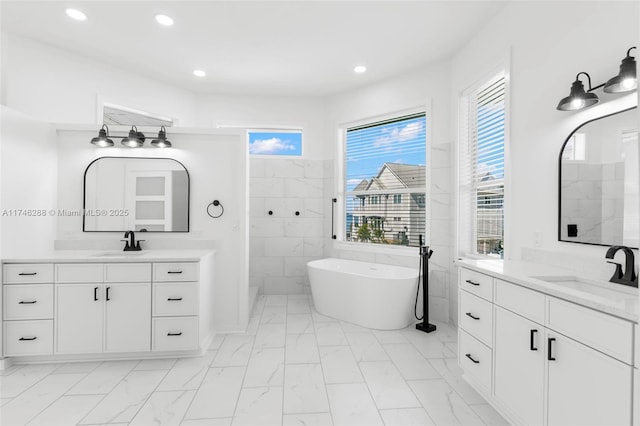 full bath with marble finish floor, a freestanding bath, a sink, and recessed lighting