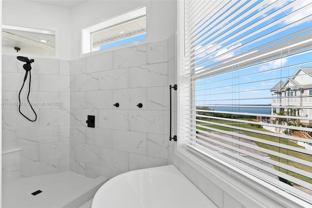 bathroom featuring tiled shower, a bathtub, and a healthy amount of sunlight