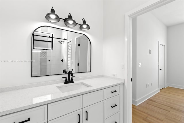 bathroom featuring baseboards, a shower stall, vanity, and wood finished floors