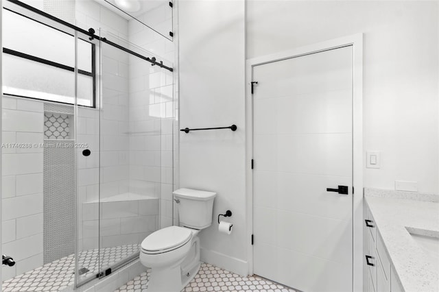 bathroom featuring toilet, a shower stall, baseboards, and vanity