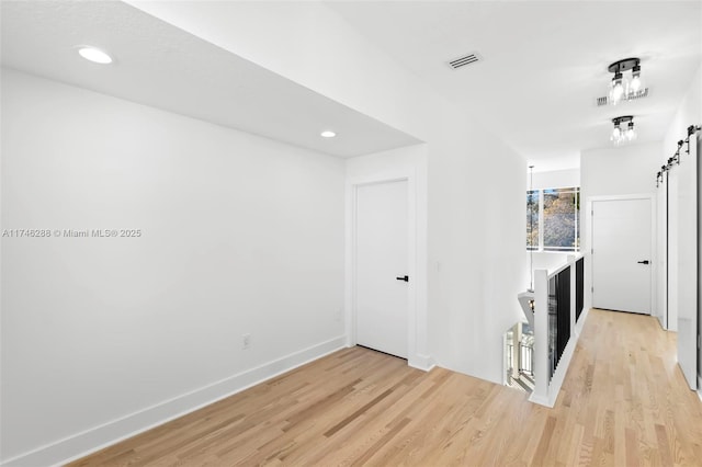 interior space with a barn door, light wood-type flooring, and visible vents