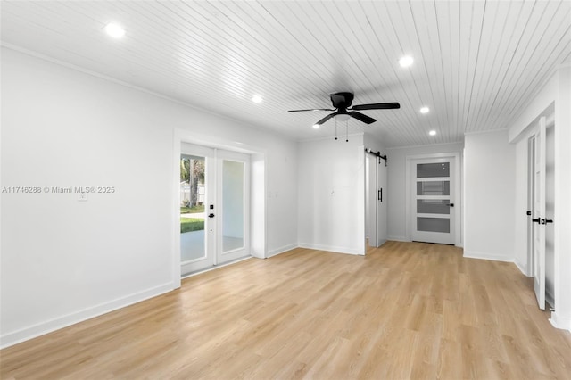 empty room featuring a barn door, recessed lighting, baseboards, french doors, and light wood finished floors