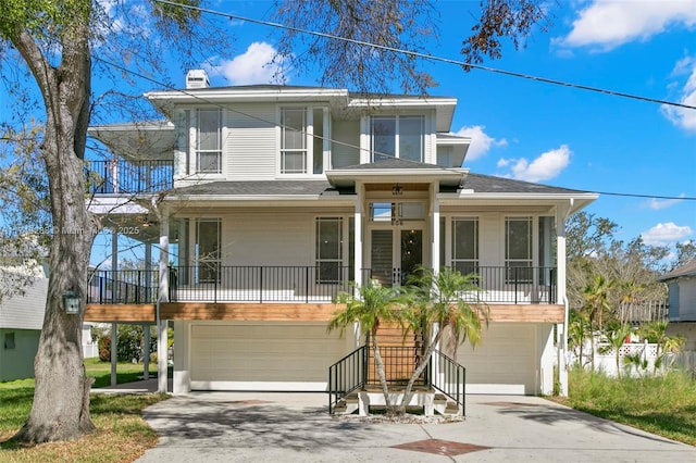 coastal inspired home featuring a garage, a chimney, covered porch, and stairway