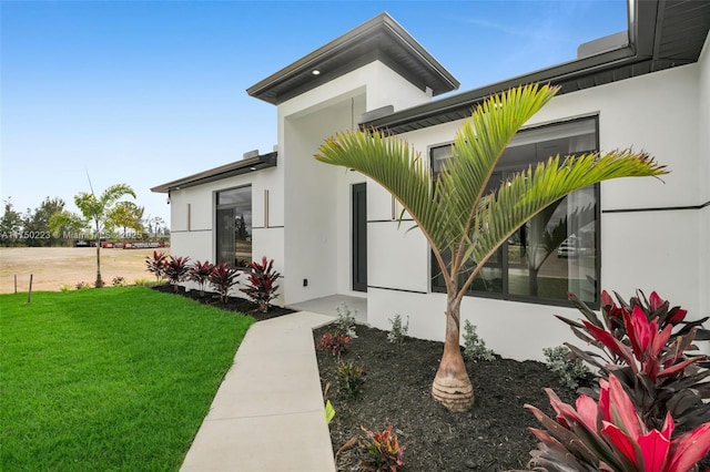 entrance to property featuring a yard and stucco siding