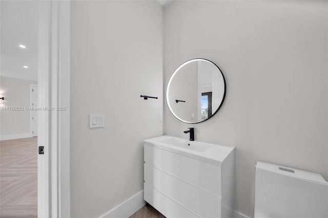 half bathroom with recessed lighting, toilet, vanity, and baseboards