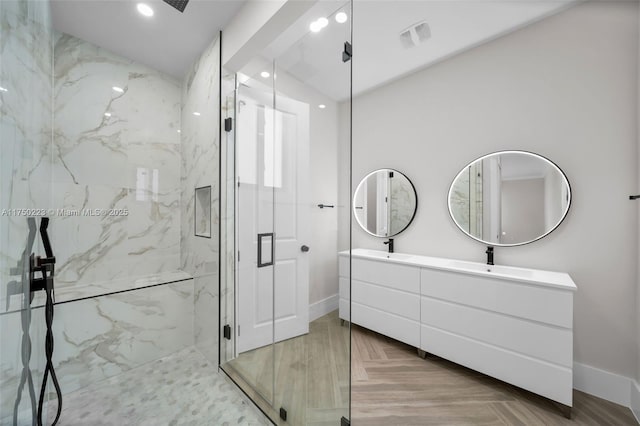 bathroom with double vanity, a marble finish shower, a sink, and recessed lighting