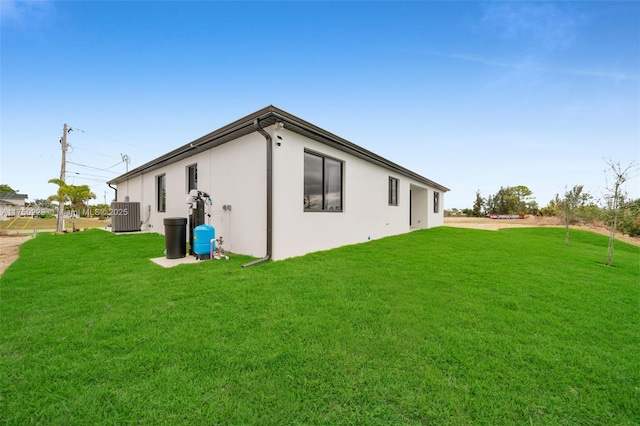 back of property with stucco siding, cooling unit, and a yard