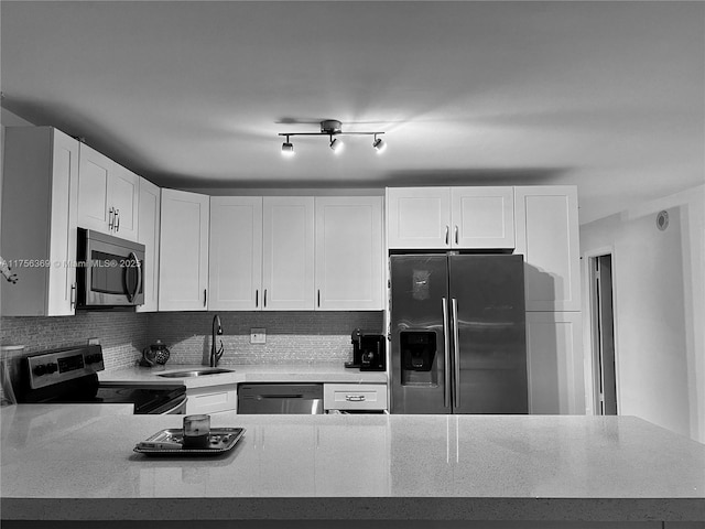 kitchen with white cabinets, a sink, stainless steel appliances, light countertops, and backsplash