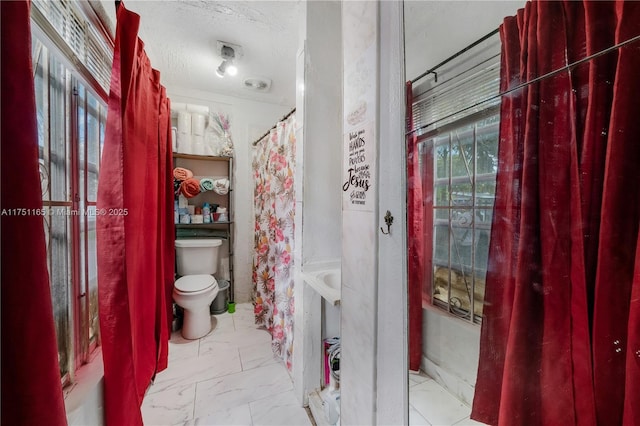 full bathroom with marble finish floor, a textured ceiling, and toilet