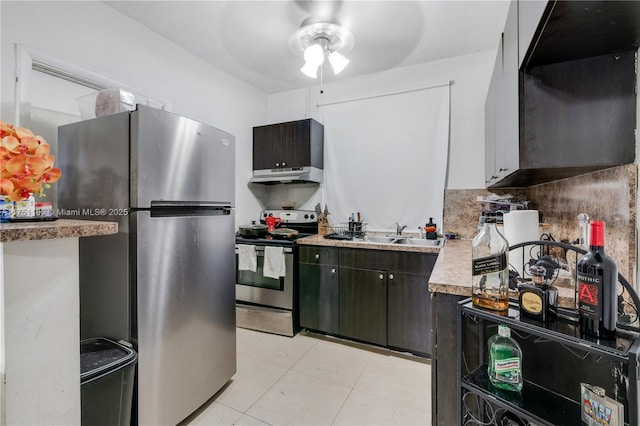 kitchen featuring a sink, stainless steel appliances, light countertops, under cabinet range hood, and backsplash