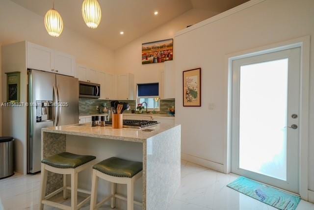 kitchen with light stone counters, a sink, stainless steel appliances, white cabinets, and backsplash