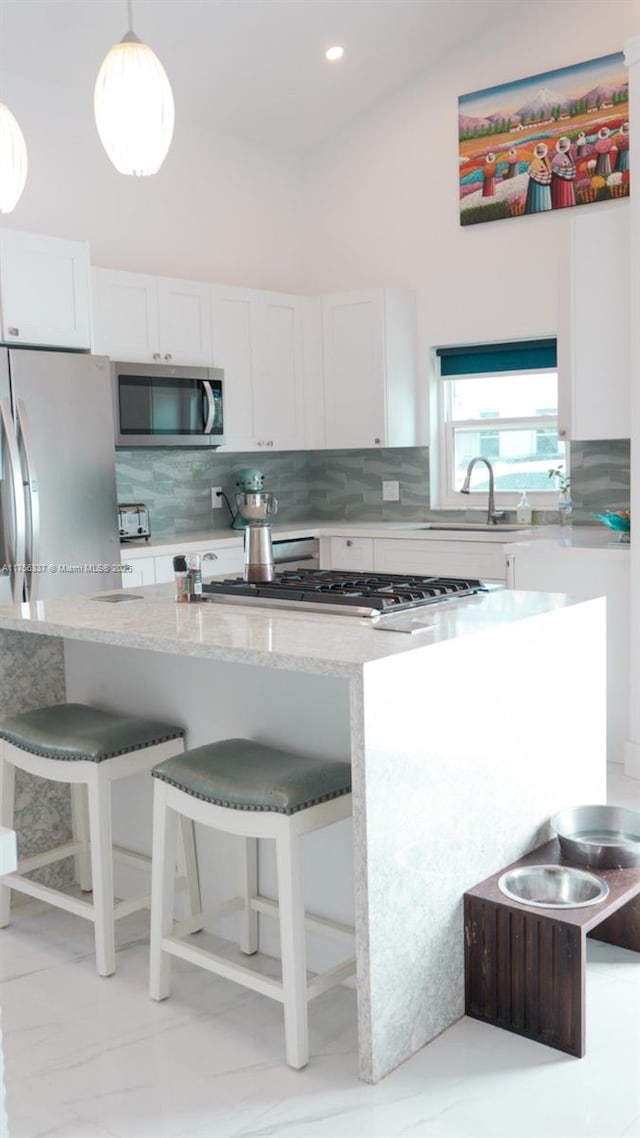 kitchen with stainless steel appliances, decorative backsplash, white cabinetry, and light stone counters