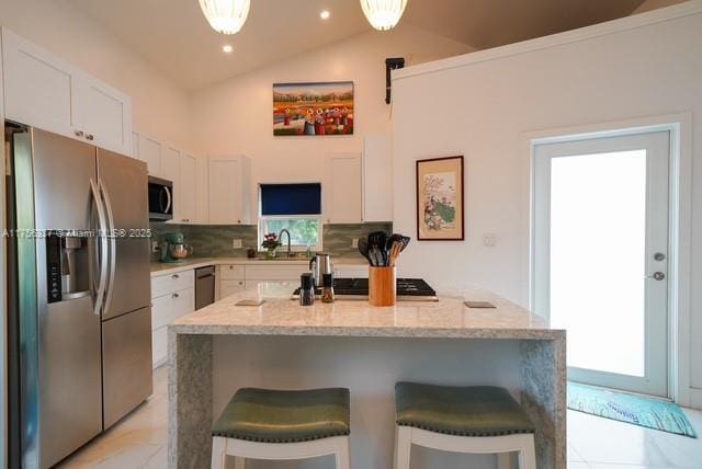 kitchen featuring appliances with stainless steel finishes, tasteful backsplash, white cabinetry, and a breakfast bar area