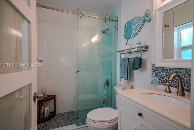 bathroom featuring vanity, backsplash, a shower stall, and toilet