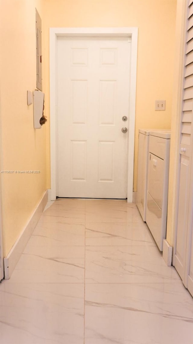 hallway with marble finish floor, washing machine and clothes dryer, electric panel, and baseboards