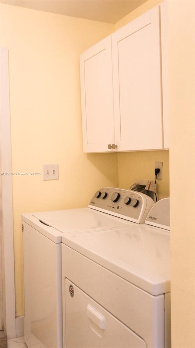 clothes washing area with washer and dryer and cabinet space