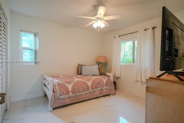 bedroom featuring baseboards, a ceiling fan, marble finish floor, and multiple windows