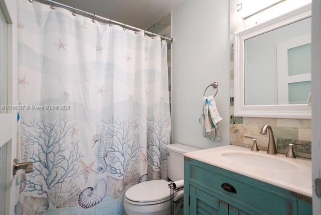 bathroom with toilet, tasteful backsplash, vanity, and a shower with shower curtain