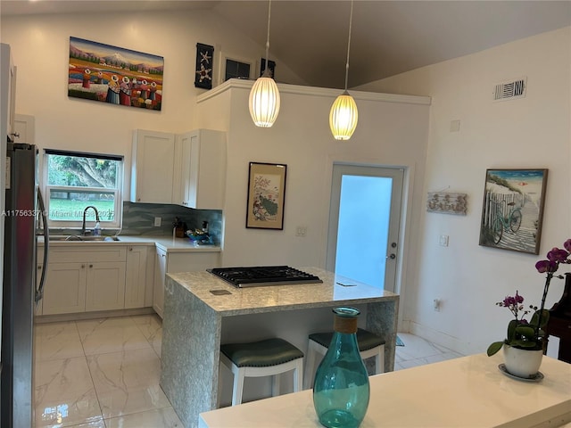 213 Florida Ave, Coral Gables, FL 33133 - kitchen featuring light marble finish floors, freestanding refrigerator, gas cooktop, a breakfast bar area, and light countertops