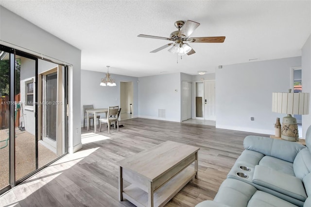 living area with a textured ceiling, wood finished floors, visible vents, and baseboards