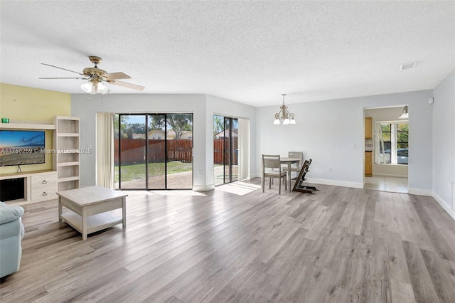 unfurnished living room featuring visible vents, a textured ceiling, baseboards, and wood finished floors