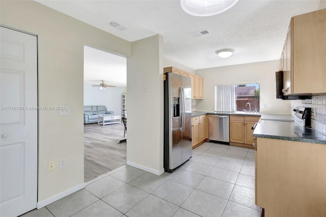 kitchen featuring stainless steel appliances, light brown cabinets, and visible vents