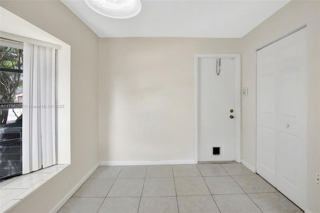 spare room featuring baseboards and light tile patterned floors