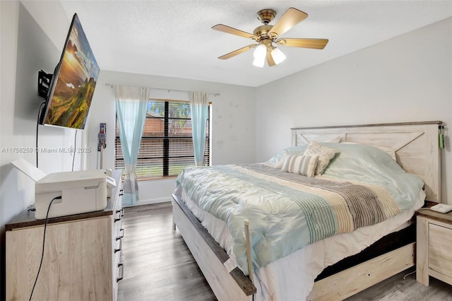 bedroom with ceiling fan, a textured ceiling, baseboards, and wood finished floors