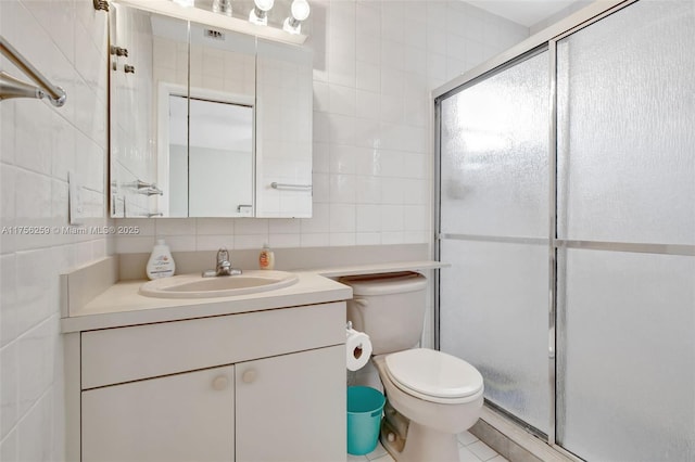 bathroom with a stall shower, tasteful backsplash, toilet, vanity, and tile walls