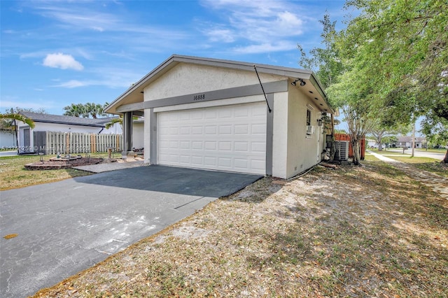 view of property exterior with a garage, fence, and stucco siding