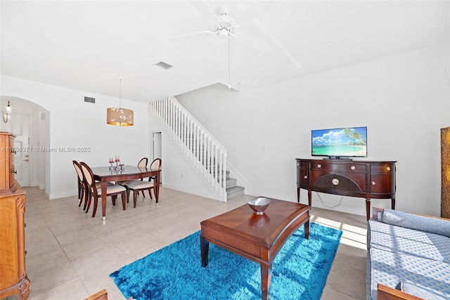 living area with stairway, visible vents, ceiling fan, and arched walkways