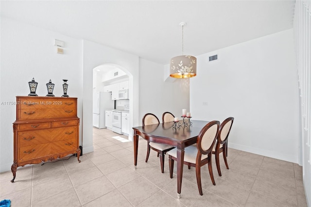 dining room featuring light tile patterned floors, arched walkways, visible vents, and baseboards